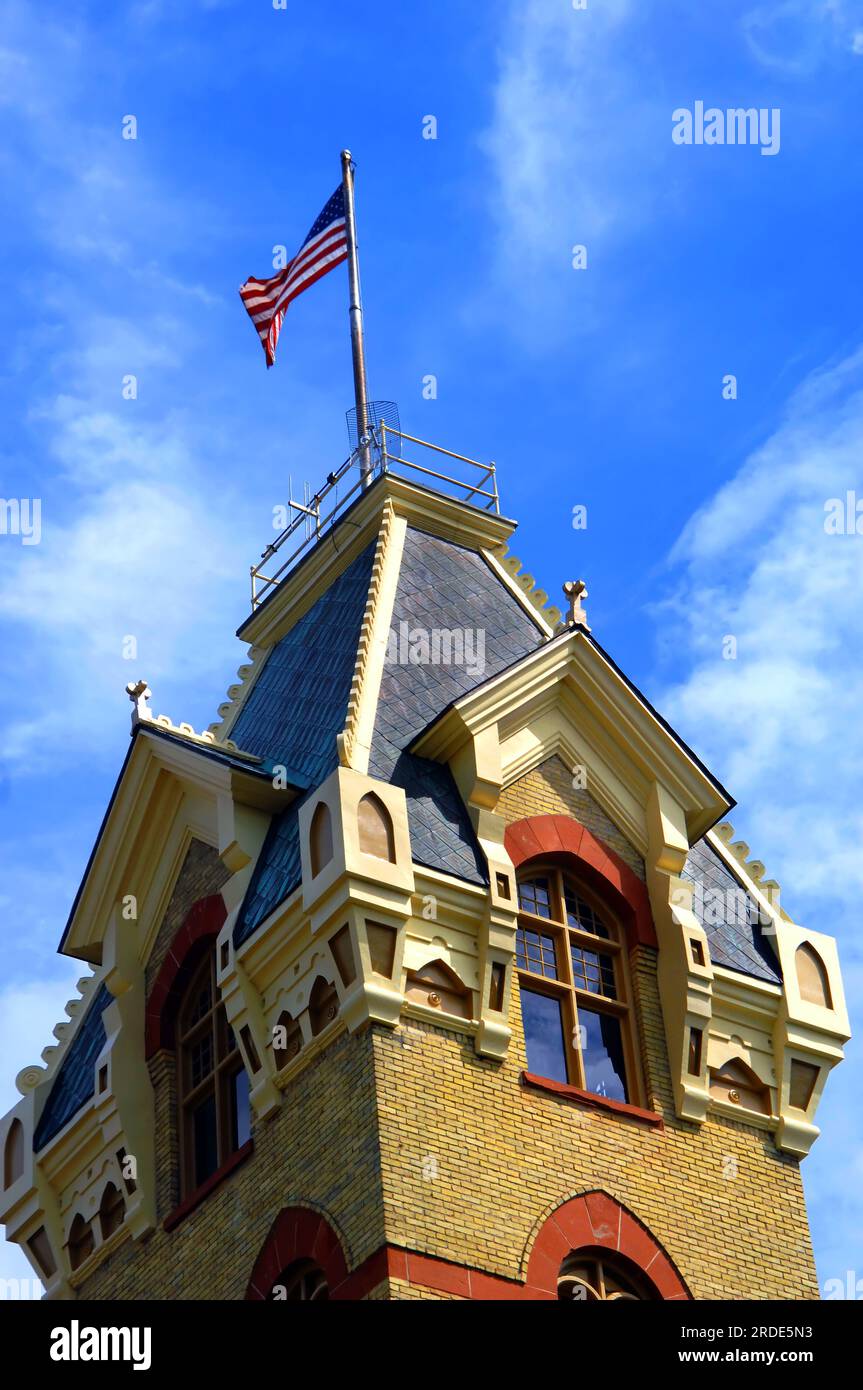 120 year old, Victorian era county courthouse in Houghton, Michigan is designed with local red sandstone and Lake Superior copper for the roof. Flag f Stock Photo