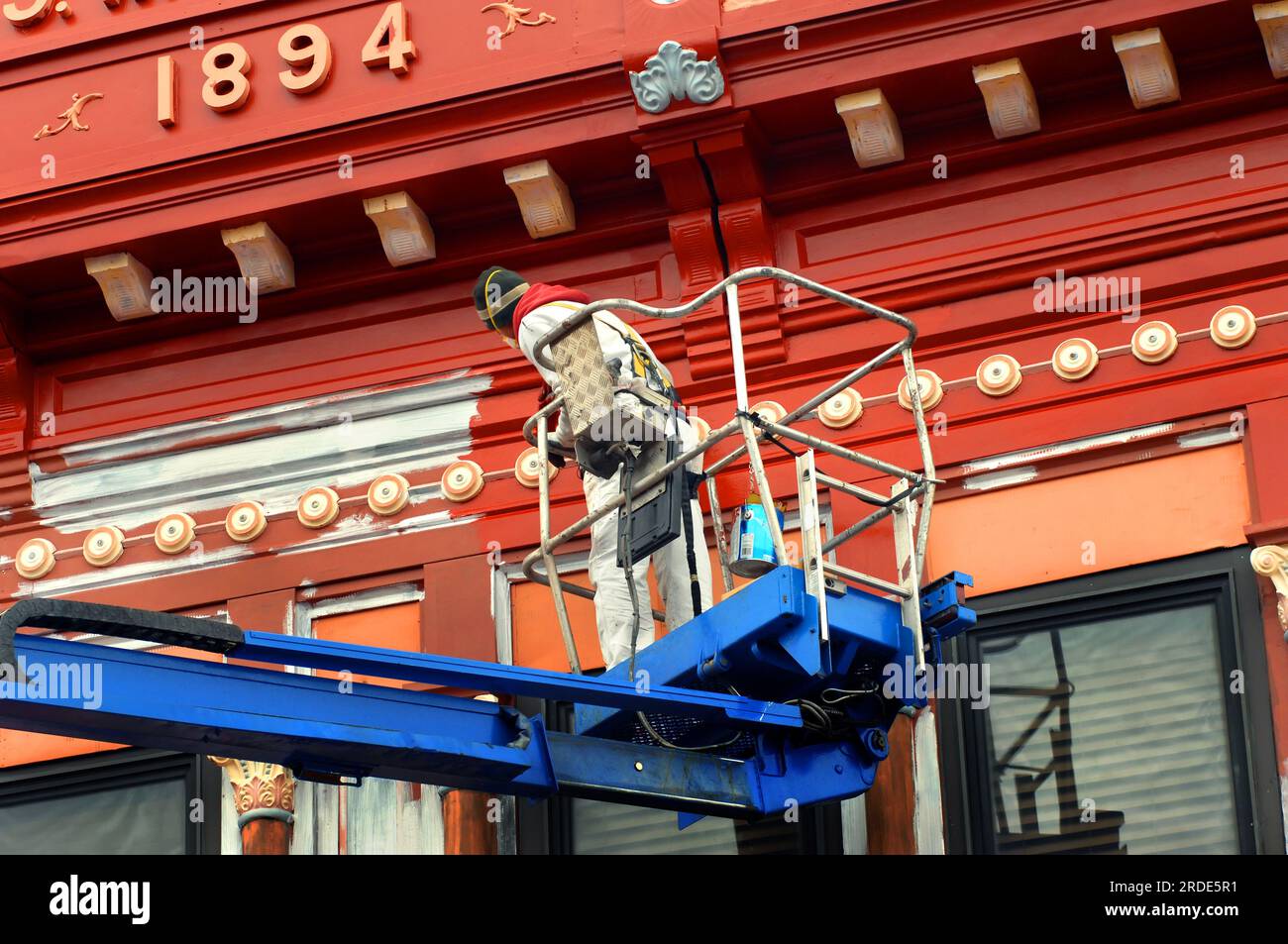 Painter applies new paint to historic building in Calumet, Michigan. He