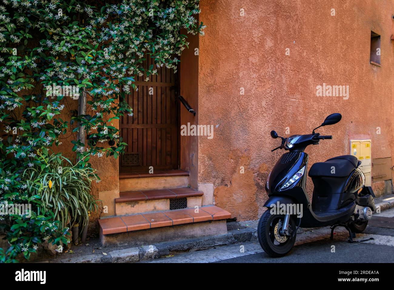 Scooter leaning against a traditional old house by the local covered provencal farmers market in the old town or Vieil Antibes, South of France Stock Photo