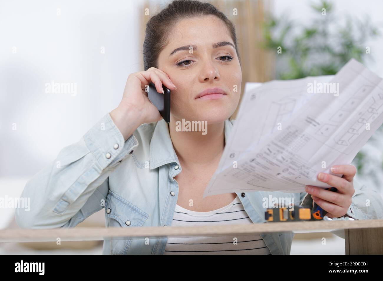 frustrated woman with self assembly furniture making telephone call