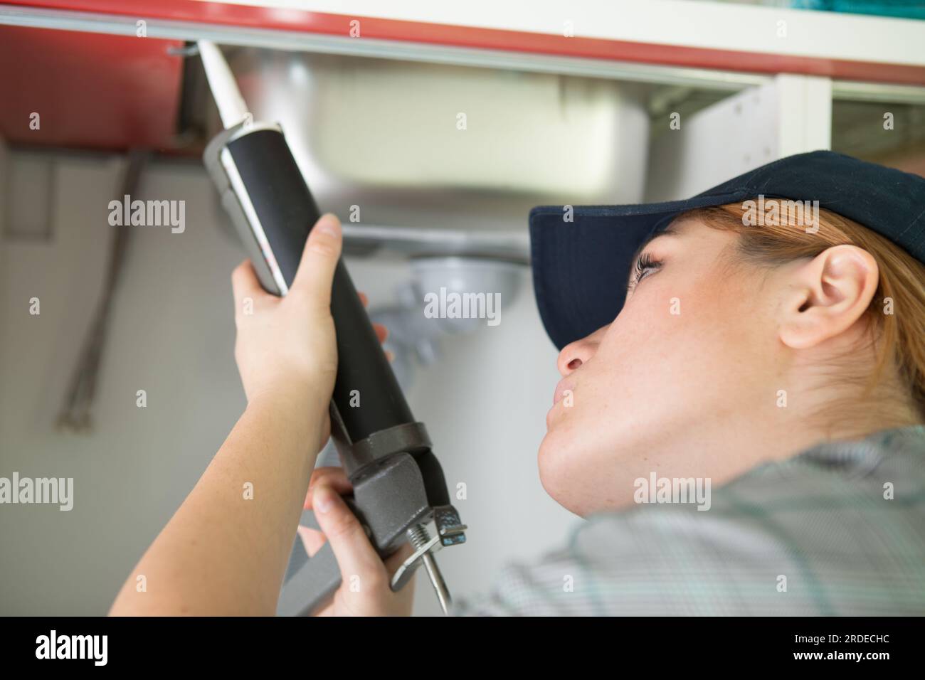 female plumber using caulking gun around a kitchen sink Stock Photo Alamy