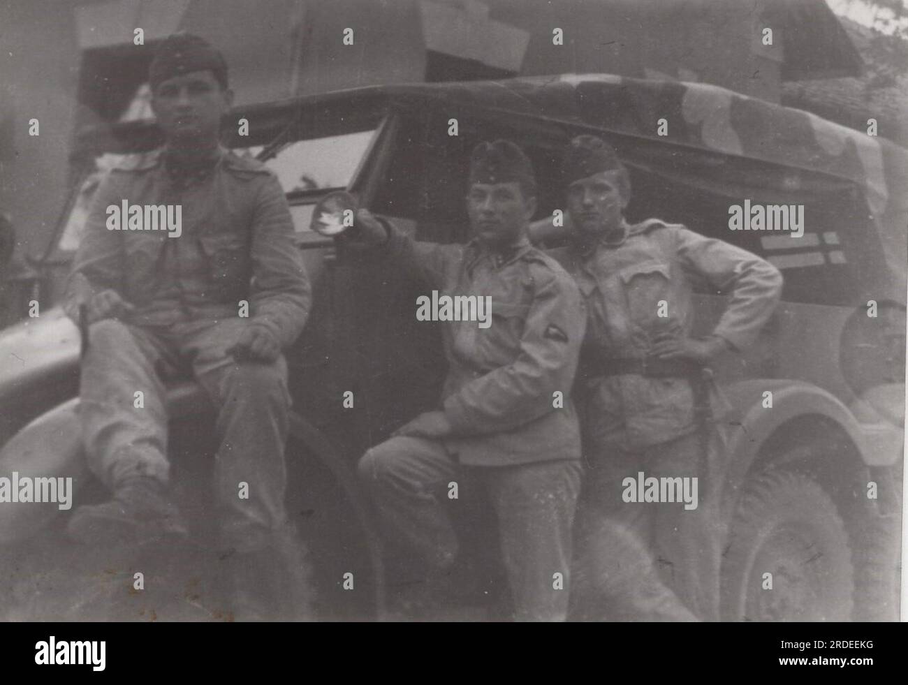young soldiers are posing in uniform with a massive military vehicle at the 1950s or 1960s. This is a commander offroad car looks very impressive. Stock Photo