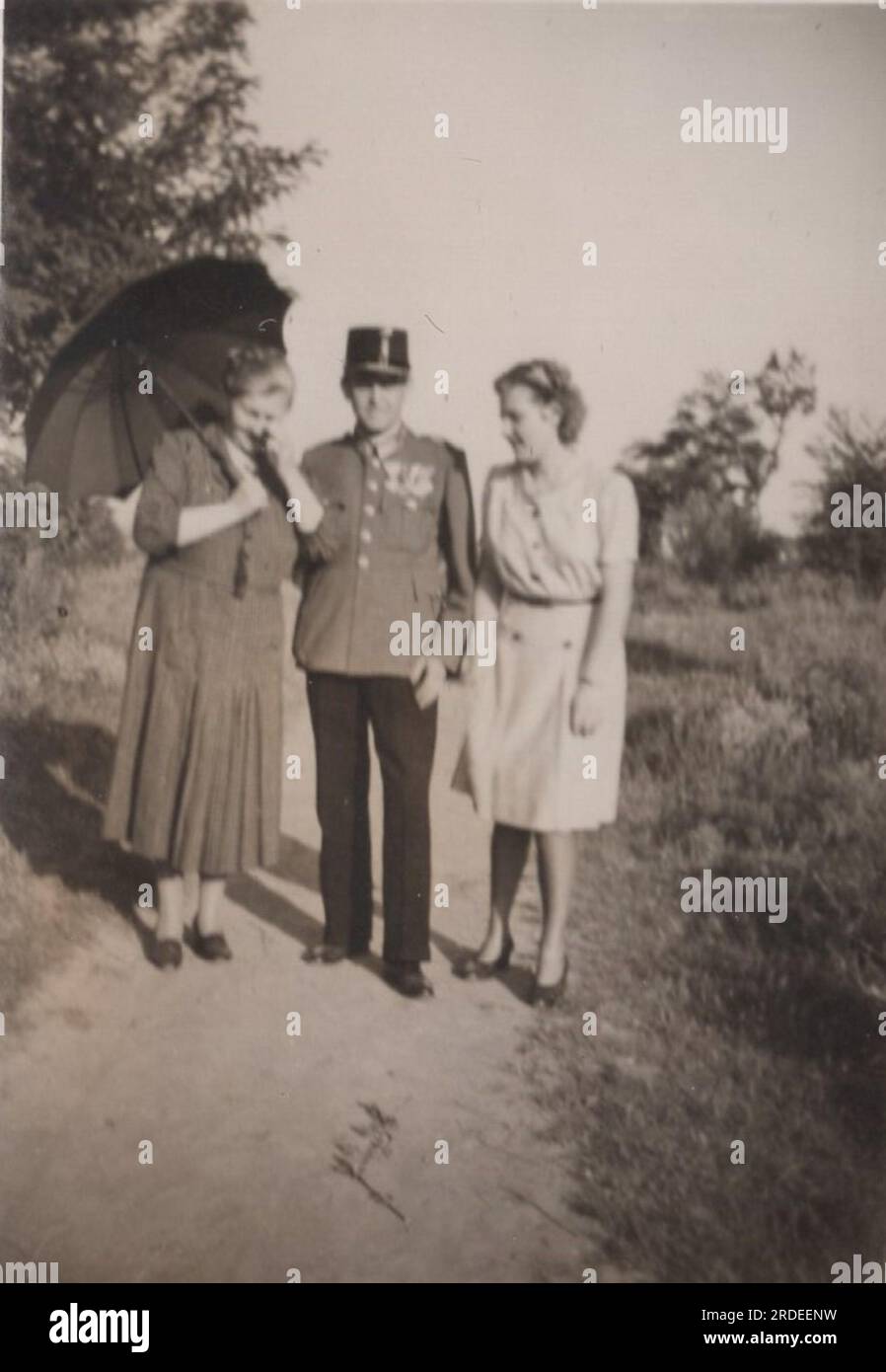 vintage family photo. Wife and daughter are standing with the soldier dad who is wearing his uniform. Summer time at 1910s Mother protected herself with un umbrella. Father has got lots of medal of Honors on his Austro-Hungarian military uniform. Stock Photo