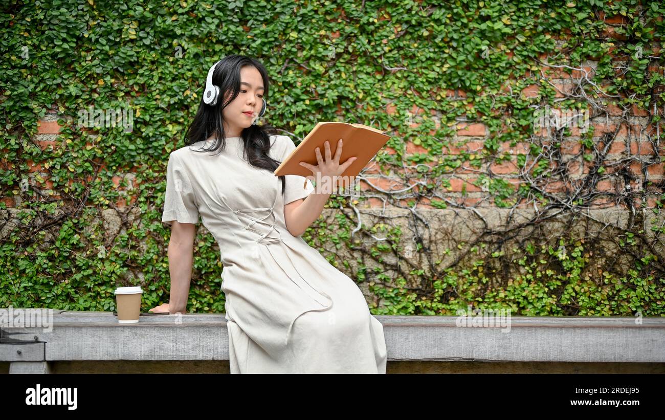 A charming and relaxed young Asian woman in a beautiful dress is ...