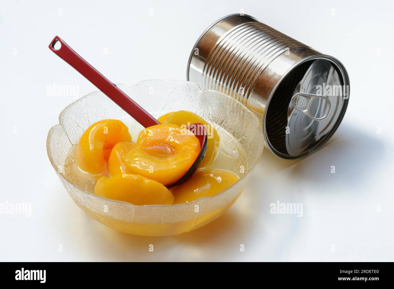 Peach, pickled peach halves in glass bowl with ladle and preserving tin Stock Photo