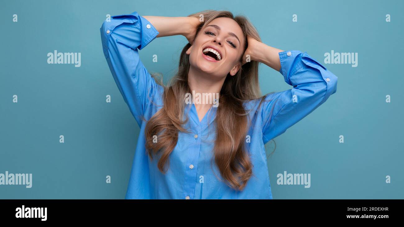 happy european well-groomed blond girl in a blue shirt isolated on a blue  background Stock Photo - Alamy