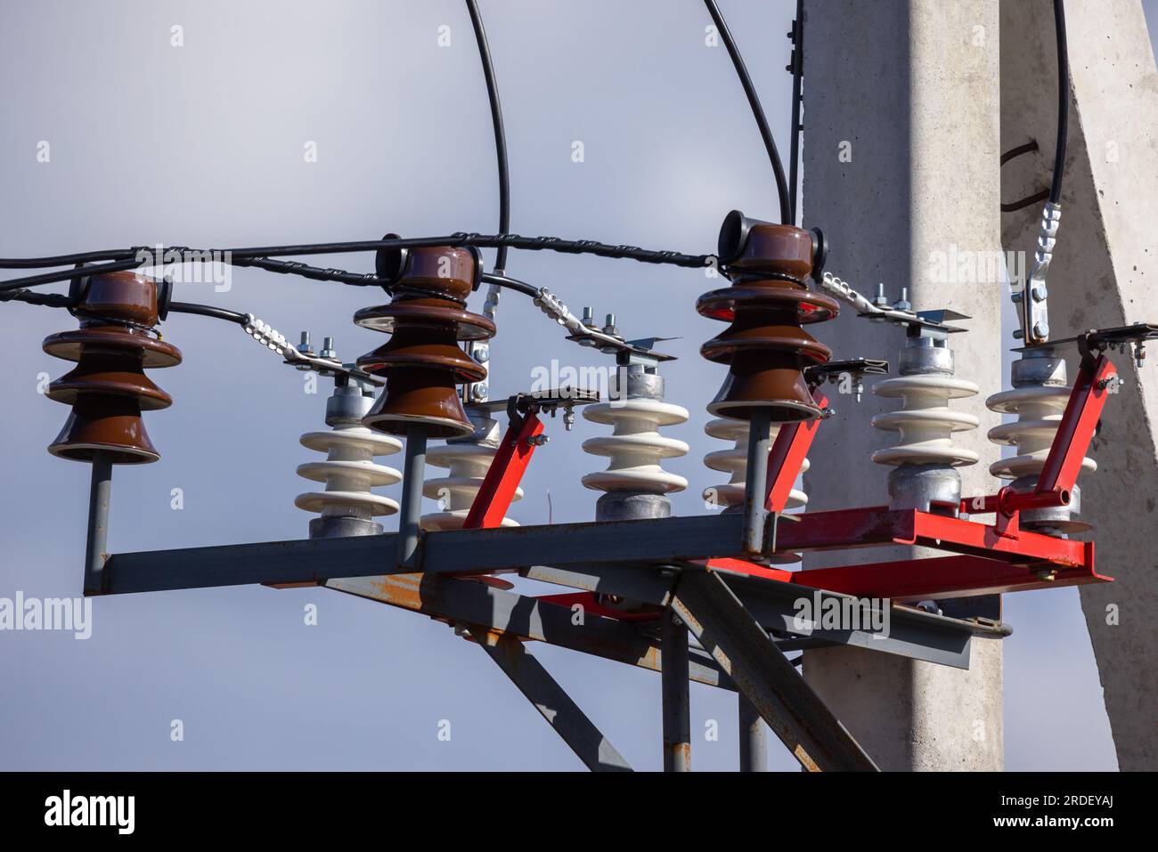 Overhead power line details. High voltage insulators and wires mounted on concrete pylon Stock Photo