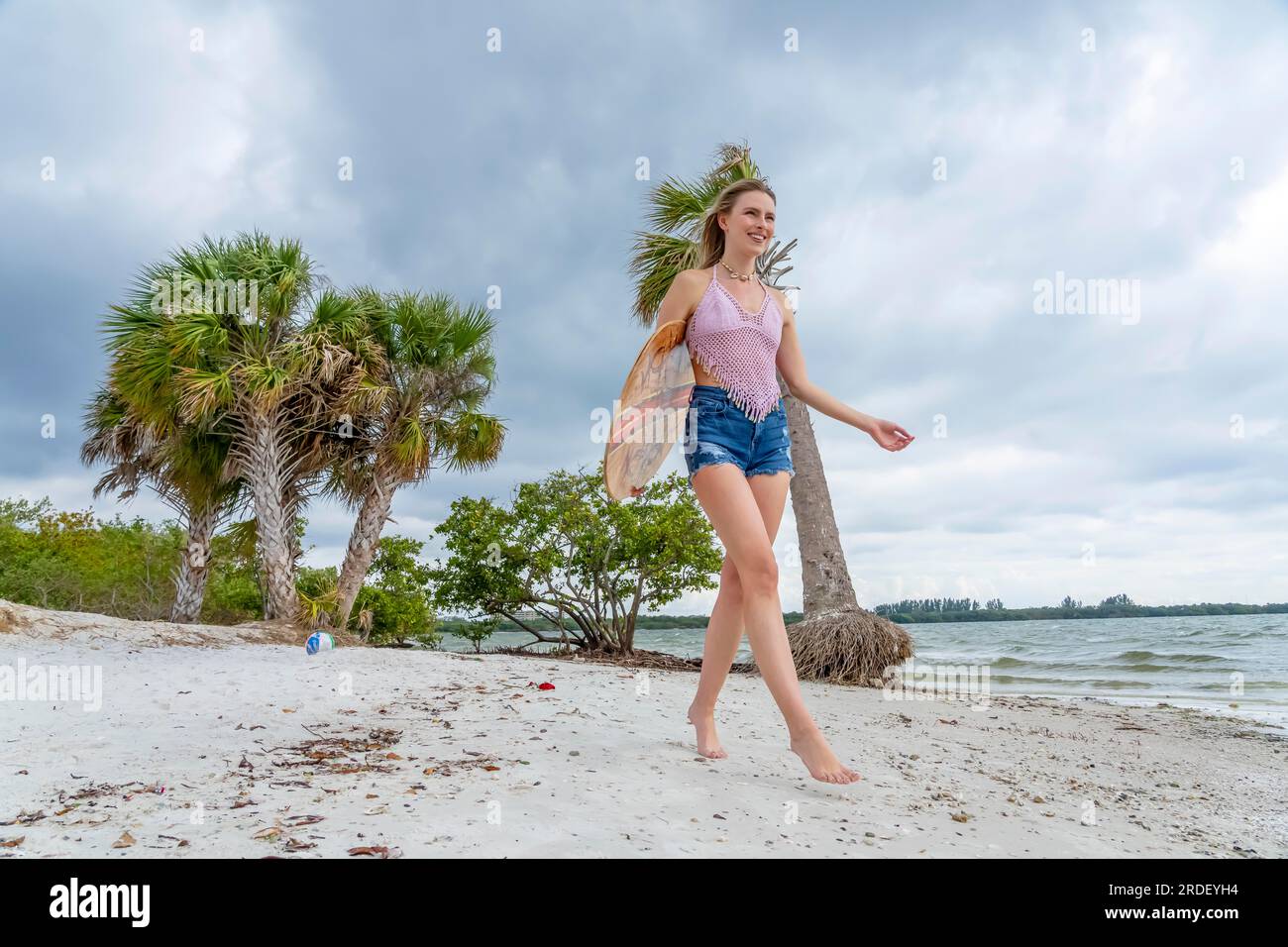 A beautiful blonde model enjoys a summers day while preparing to surf on the ocean with her boogie board Stock Photo