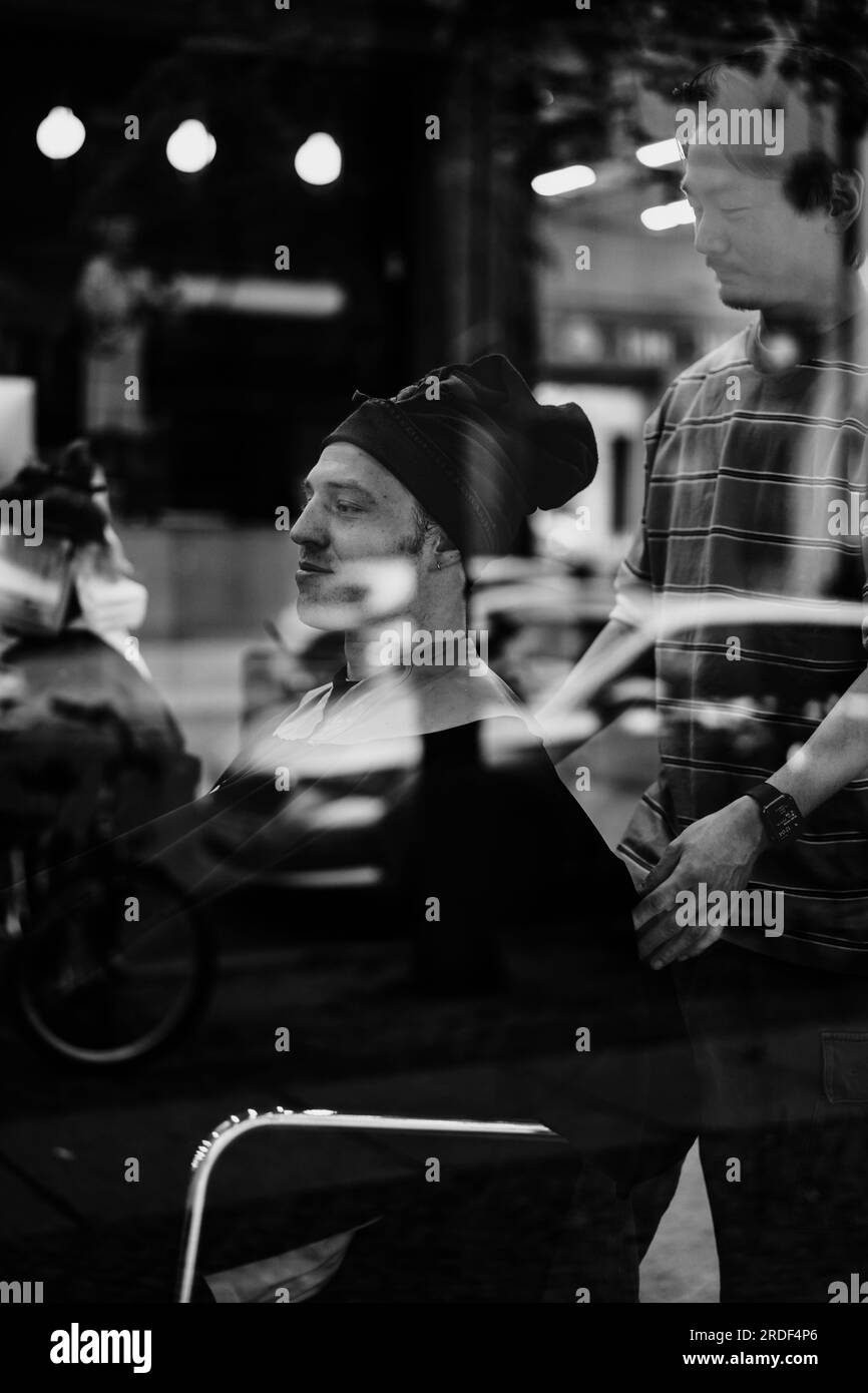 Man in a barbershop cutting his hair, shot through glass. Stock Photo