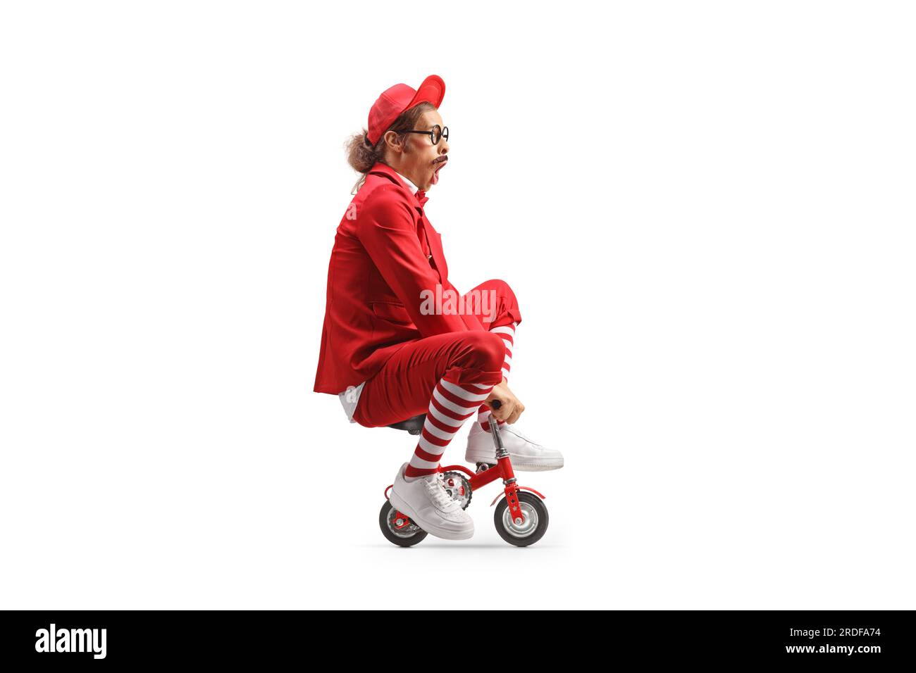 Comedian riding a small red bike isolated on white background Stock Photo
