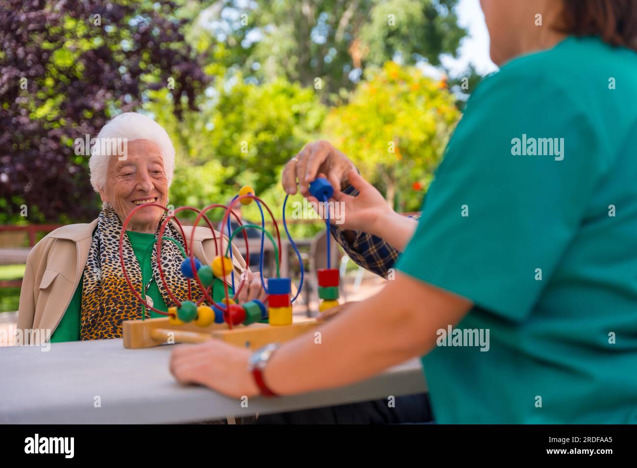 Hands of two elderly people in the garden of a nursing home or retirement home playing with games to improve the mobility of the hands smiling Stock Photo