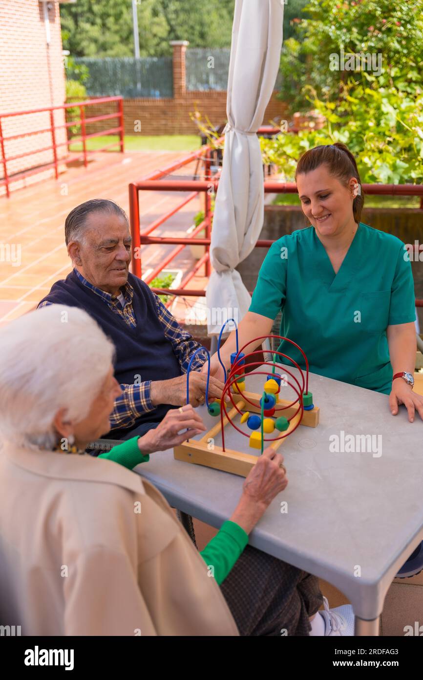Two elderly people in the garden of a nursing home or retirement home playing with games to improve the mobility of the hands Stock Photo