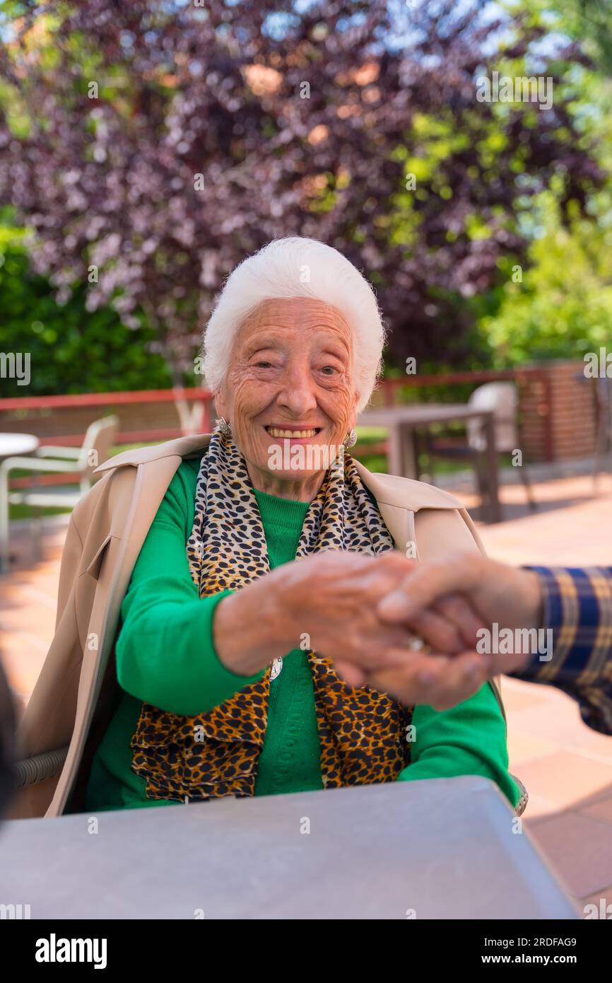 Hands of two elderly people in the garden of a nursing home or retirement holding hands in a moment of affection Stock Photo