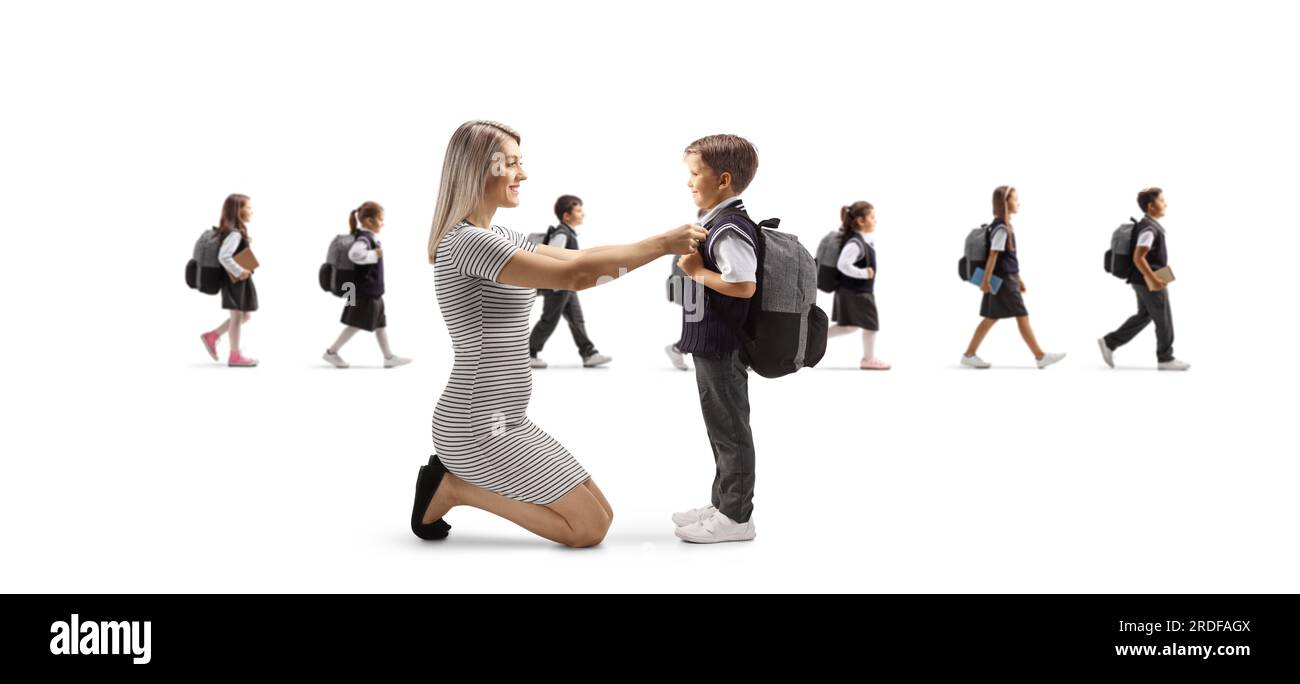 Mother helping son getting ready for school and other children walking in the back isolated on white background Stock Photo