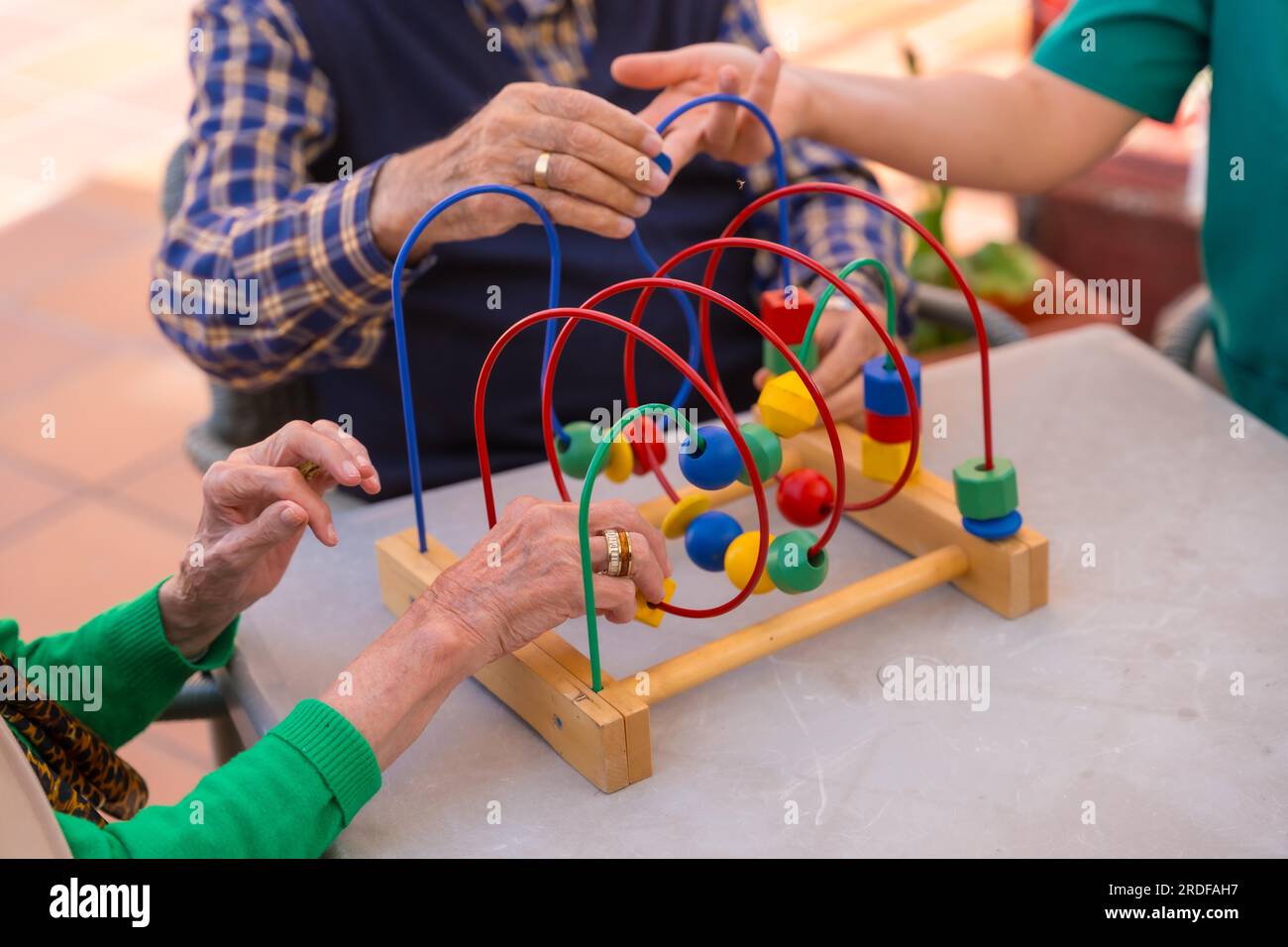 Hands of two elderly people in the garden of a nursing home or retirement home playing with games to improve the mobility of the hands Stock Photo