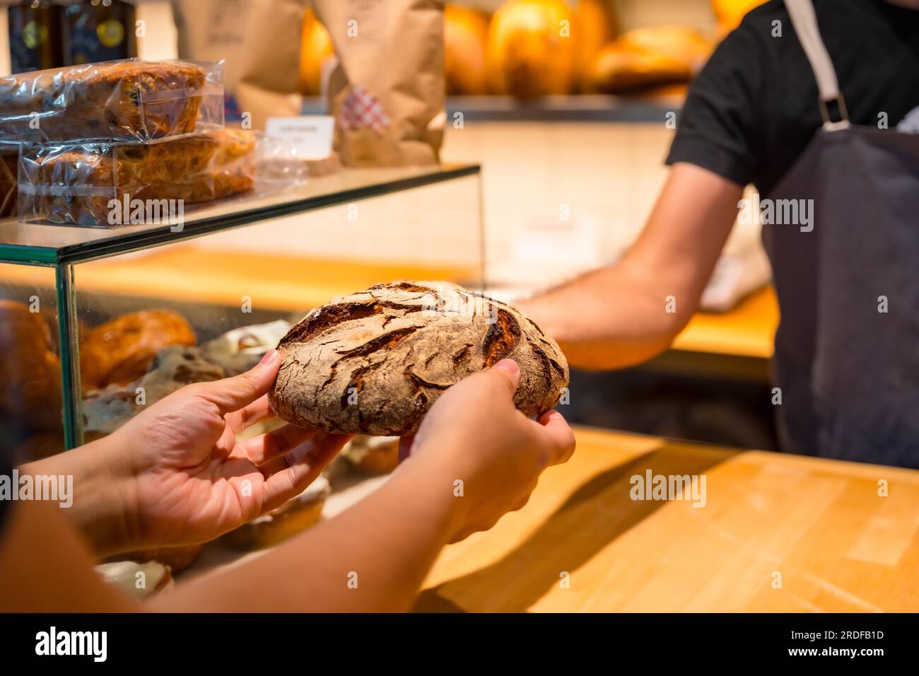 Customer hands in the bakery shop buying a loaf from the baker in the