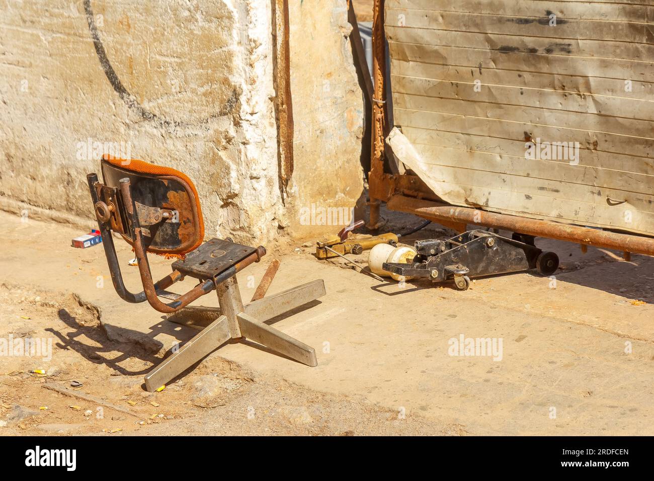 Havana, Cuba - May 27, 2023:  The chair of a security guard. The rare object is by a damaged or broken gargage door where a jack supports the structur Stock Photo