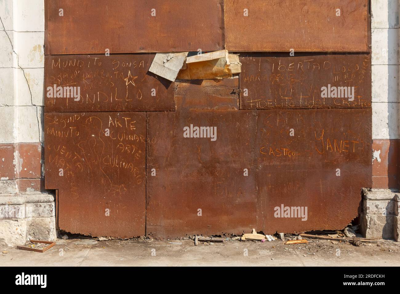 Havana, Cuba - May 27, 2023:  A rusty metallic large door of a garage. A broken part of the door is covered with cardboard. Stock Photo