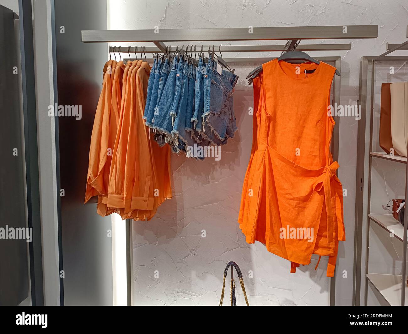 https://c8.alamy.com/comp/2RDFMHM/womens-clothing-store-summer-collection-an-orange-summer-dress-denim-shorts-and-cotton-shirts-hang-on-hangers-collection-of-stylish-womens-clothe-2RDFMHM.jpg