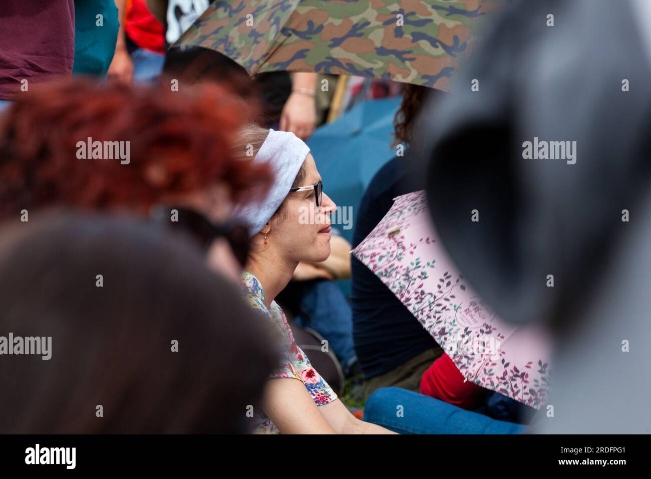 Gattatico, Reggio Emilia, Italy - April 25, 2023: Side view of girls friends watching concert in the park at open air Stock Photo
