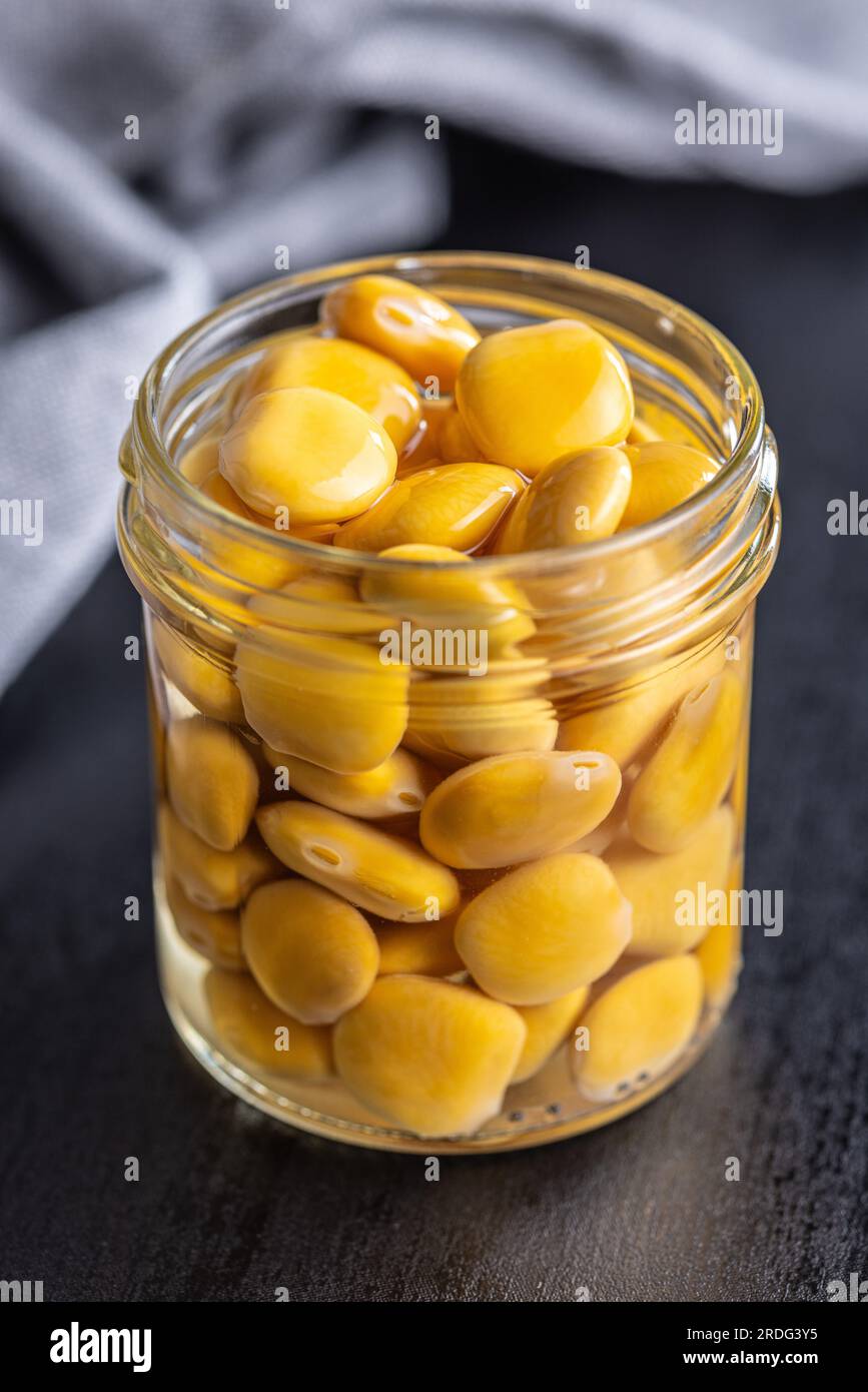 Lupini beans in brine. Pickled lupin in jar on the black table Stock