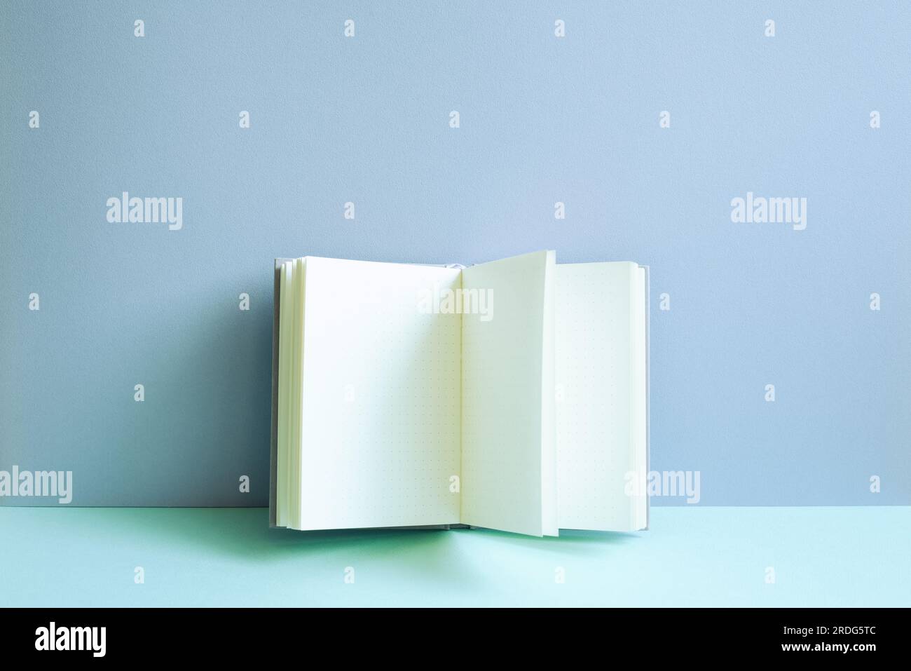 Open notebook on blue desk. blue wall background Stock Photo