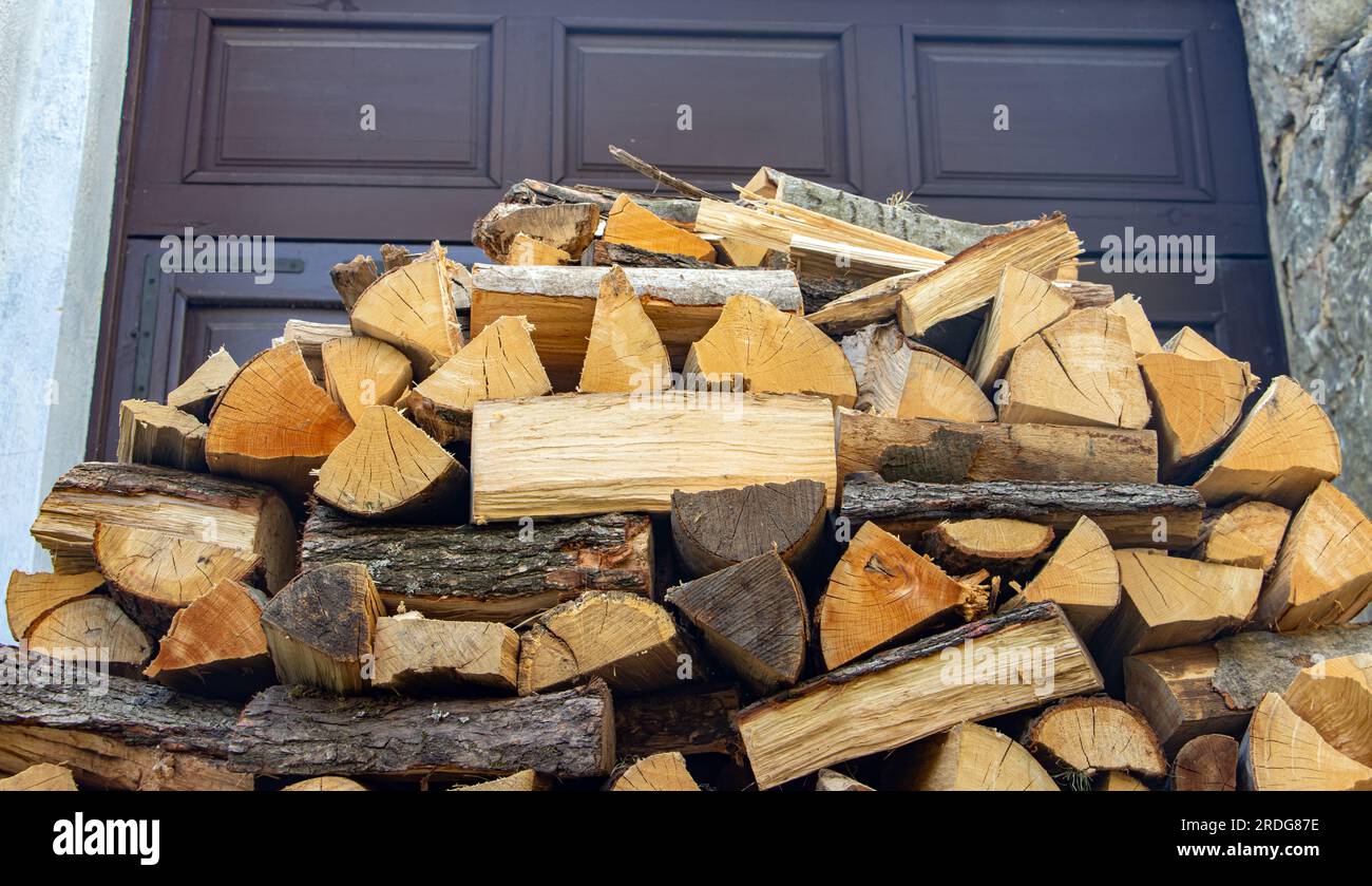 Firewood in a pile in front of a gate in the yard. Stock Photo