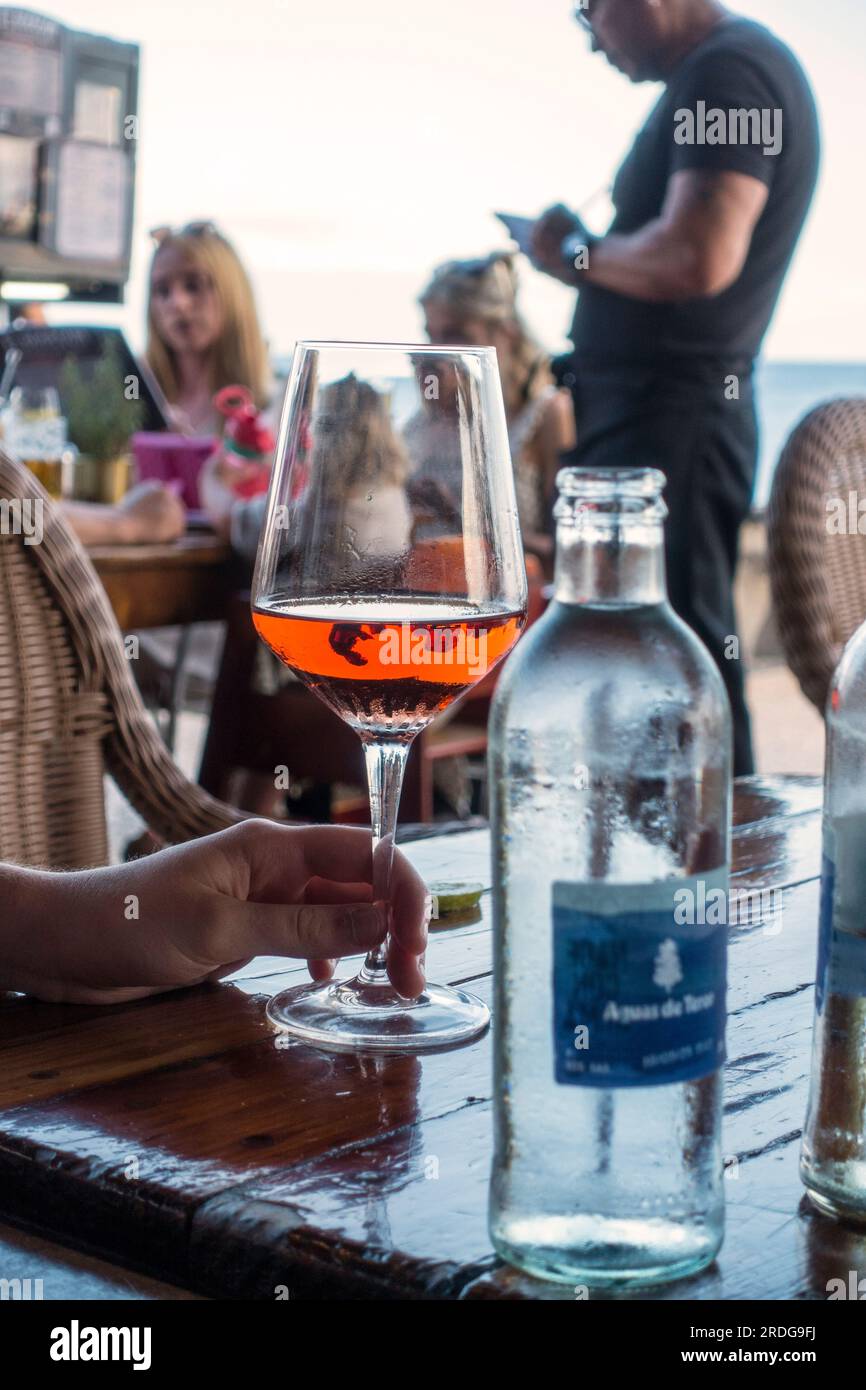 A glass of rosé wine, in a restaurant,  with waiter in the background Stock Photo
