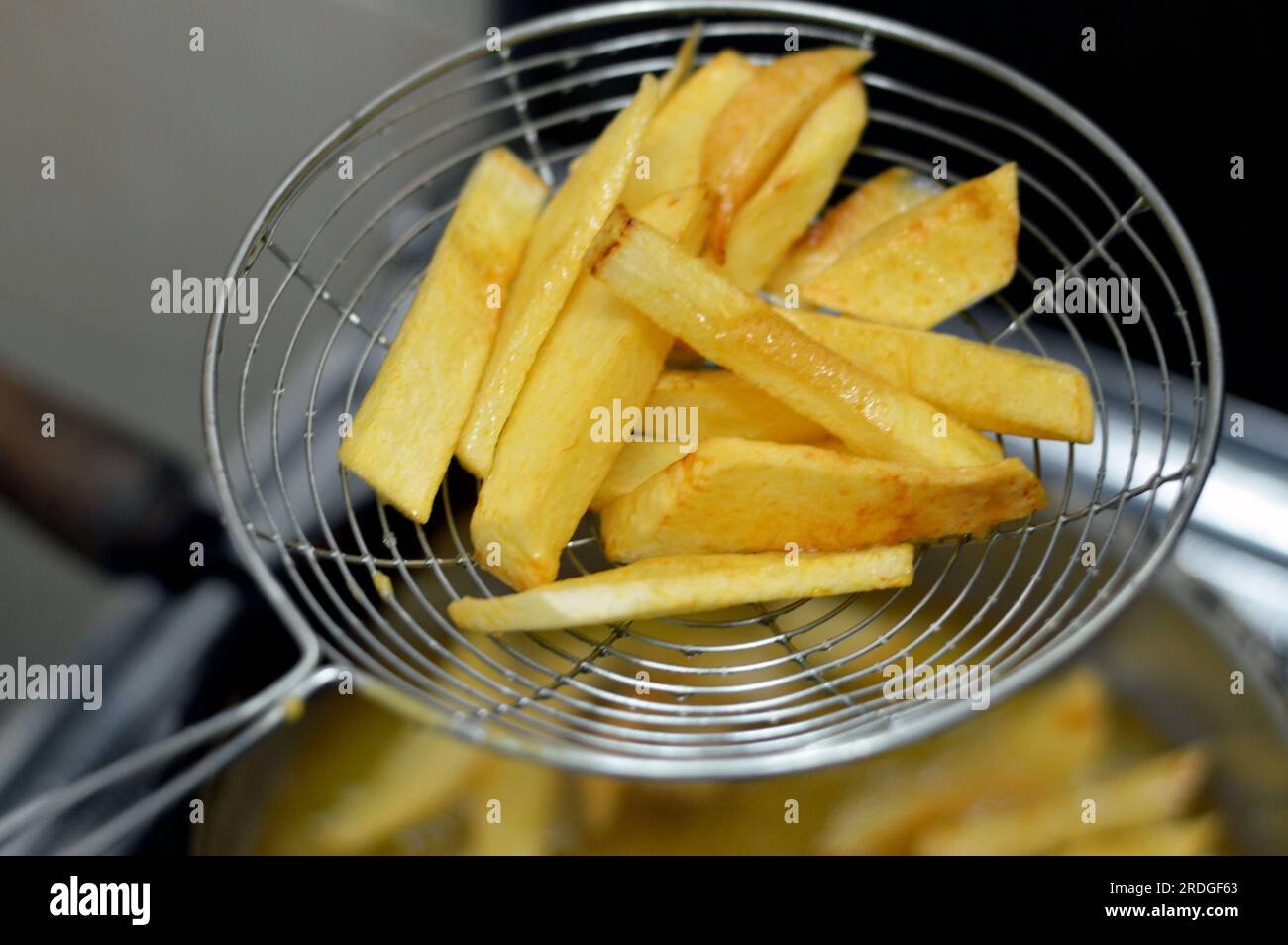 Close up of French fries potatoes fried in boiling hot oil in a deep