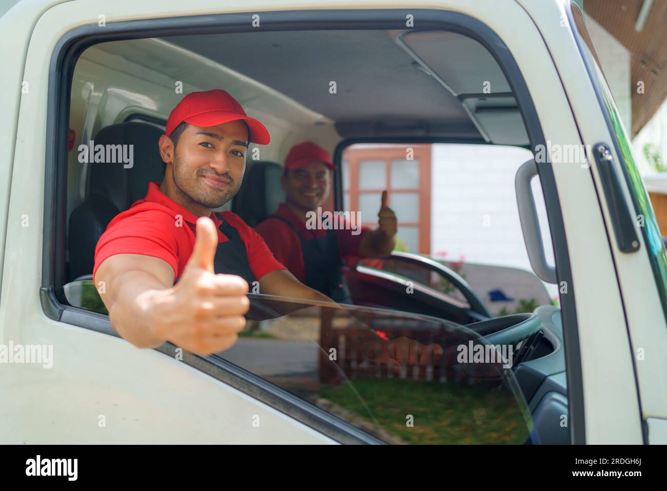 transport worker sits in the cargo truck, smiling with readiness and dedication as they embark on the move to a new house. Their enthusiasm and commit Stock Photo