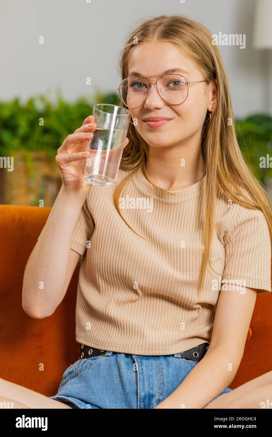 Thirsty woman holding glass of natural aqua make sips drinking still