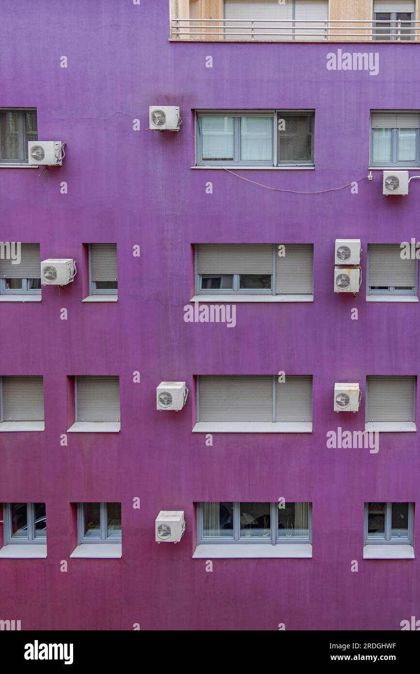 Split Air Conditioners Hanging at Purple Building Facade Stock Photo