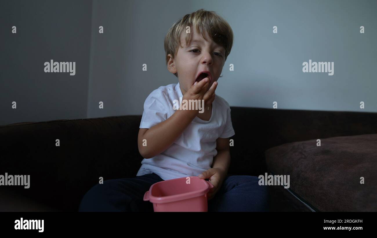 Little boy snacking food sitting on couch Stock Photo - Alamy