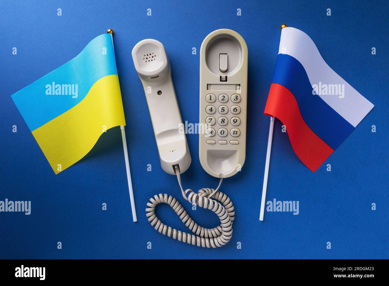 Old telephone and two flags on a blue background, a concept on the theme of telephone conversations between the Ukraine and Russia Stock Photo