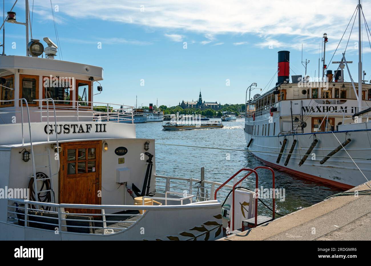 traditional white cruising ships at the quai in the harbour of Stockholm with the nordic museum in the background, Sweden Stock Photo