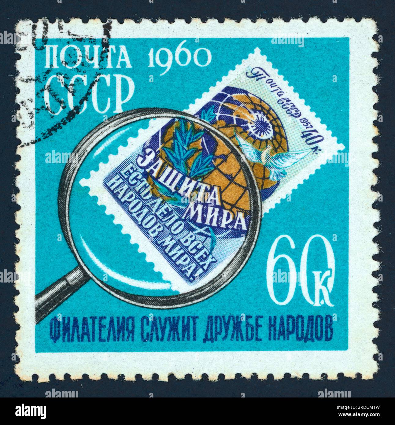 A postage stamp issued in the USSR in 1960 for the International Collectors' Day. The turquoise stamp features a postage stamp under a magnifying glass. The smaller stamp within a stamp features the text: 'защита мира есть дело всех народов мира' 'Defending peace in the world is all nations' work'. The text 'Филателия служит дружбе народов' – 'Philately serves the friendship of peoples' is printed below. Face value: 60K (60 kopeks). Stock Photo