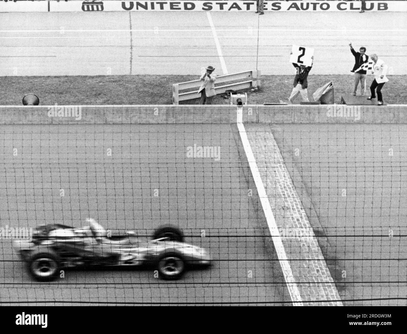 Indianapolis, Indiana:  May 30, 1970 Al Unser, driving car #2, speeds across the finish line and receives the checkered flag signal for victory at the annual Formula 1 Indianapolis 500 race. Stock Photo