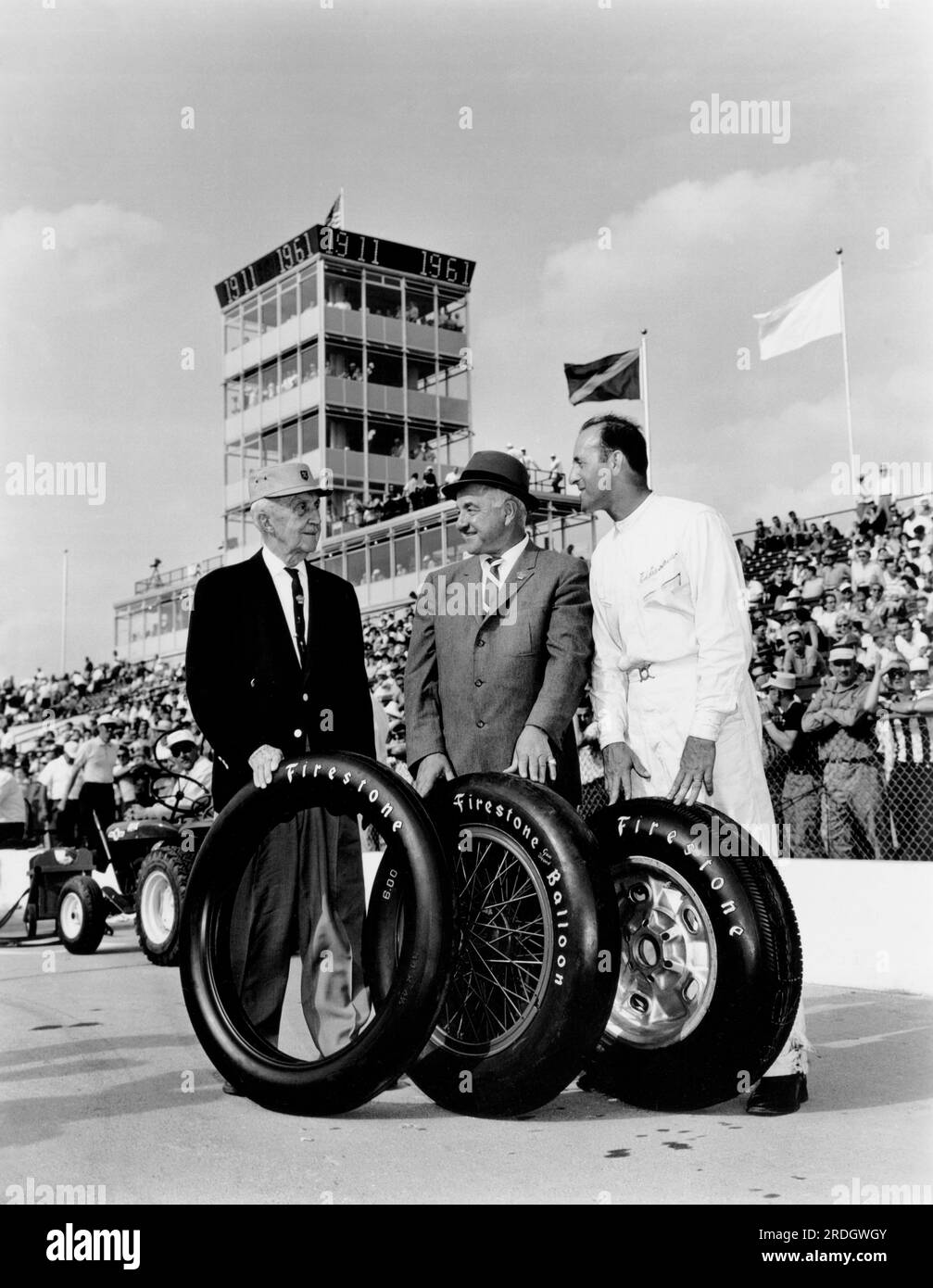 Indianapolis, Indiana:  May, 1961 Three generations of Indy 500 race car drivers and the Firestone tires they drove on pose at the 50th anniversary of the race. Left to right: Ray Harroun, winner of the first  Indy 500 in 1911; Peter De Paolo, winner of the 1925 event and the first to average more than 100 mph for the race, as well as the first driver to win using low pressure balloon tires; and Eddie Sachs, winner of the pole position for the second straight year. Stock Photo