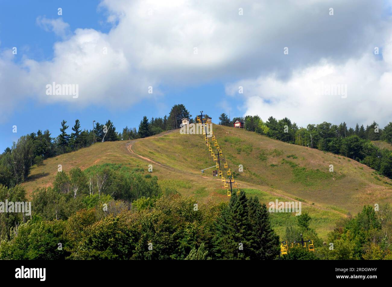 Michigan Tech ski lift is surrounded by summer.  Yellow ski lift chairs descend to bottom of Quincy Hill in Upper Peninsula, Michigan. Stock Photo