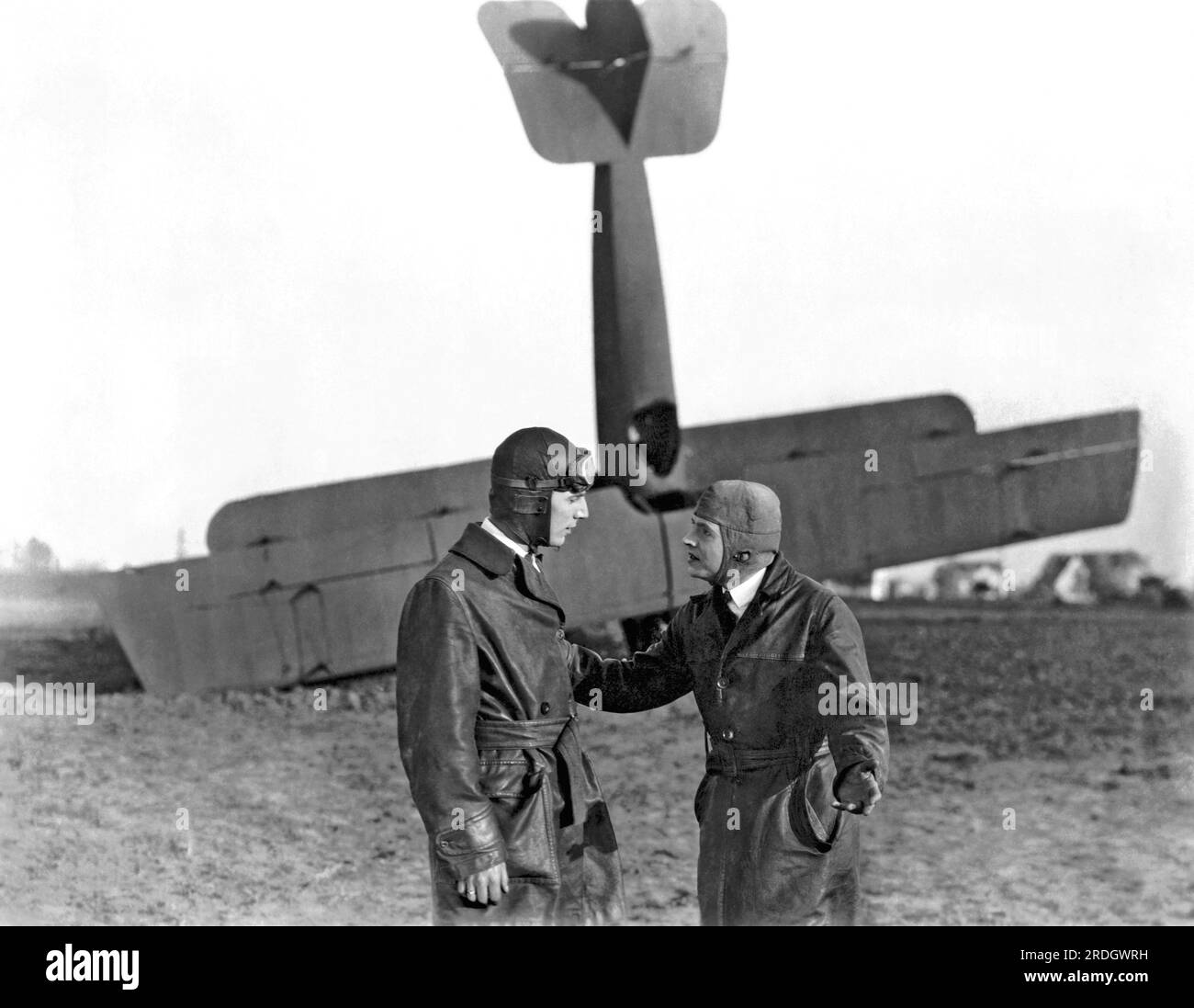 Hollywood, California:  c. 1917 Two pilots discussing their bi-plane which is nose down in the background Stock Photo