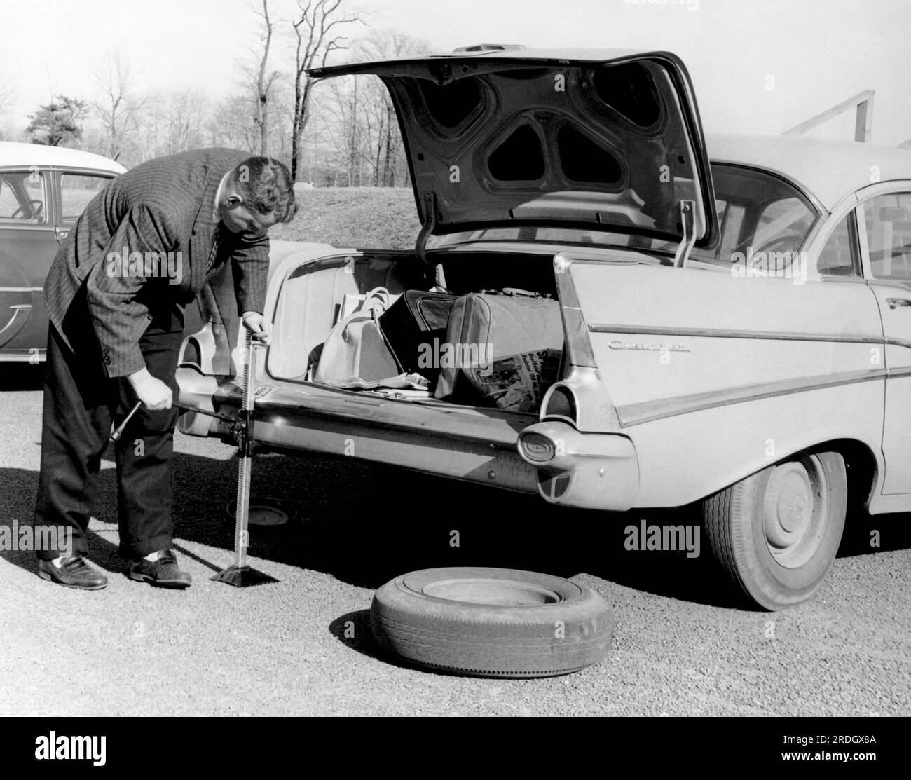 united-states-1958-a-man-jacking-up-his-1957-chevrolet-to-change-a