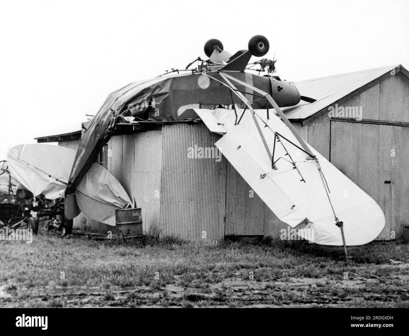 Dundee, Mississippi:  May 21, 1962 A small plane that appears to have just gotten weary of flying was actually picked up by a tornado and deposited upside down on a hangar. Stock Photo