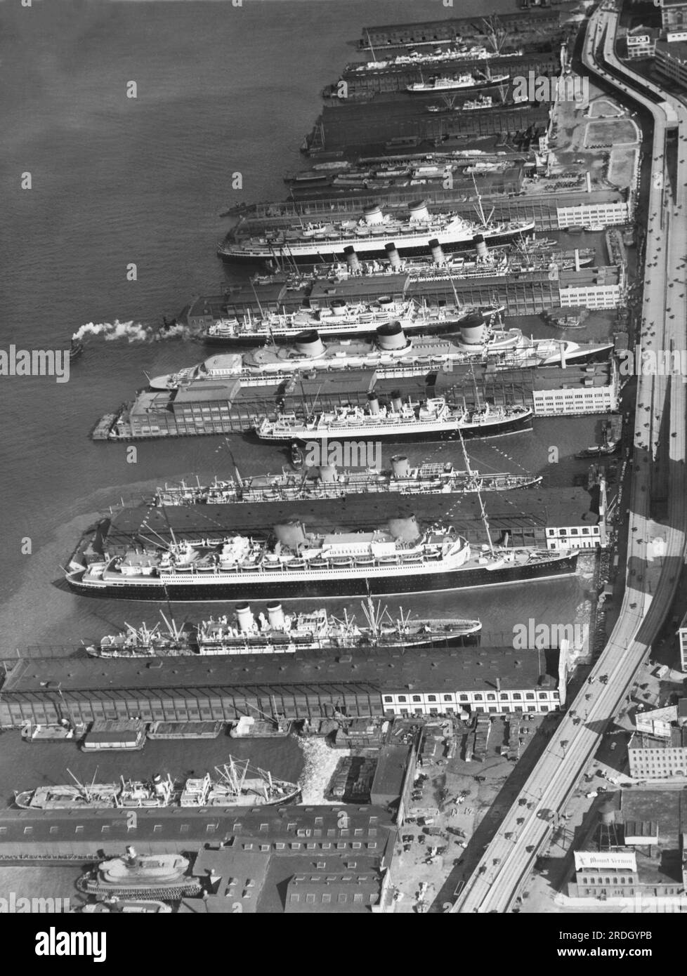 New York, New York:   c. 1932 A lineup of ships in the harbor. Near the center are the passenger liners, 'SS Normandie' and SS Bremen'. Stock Photo
