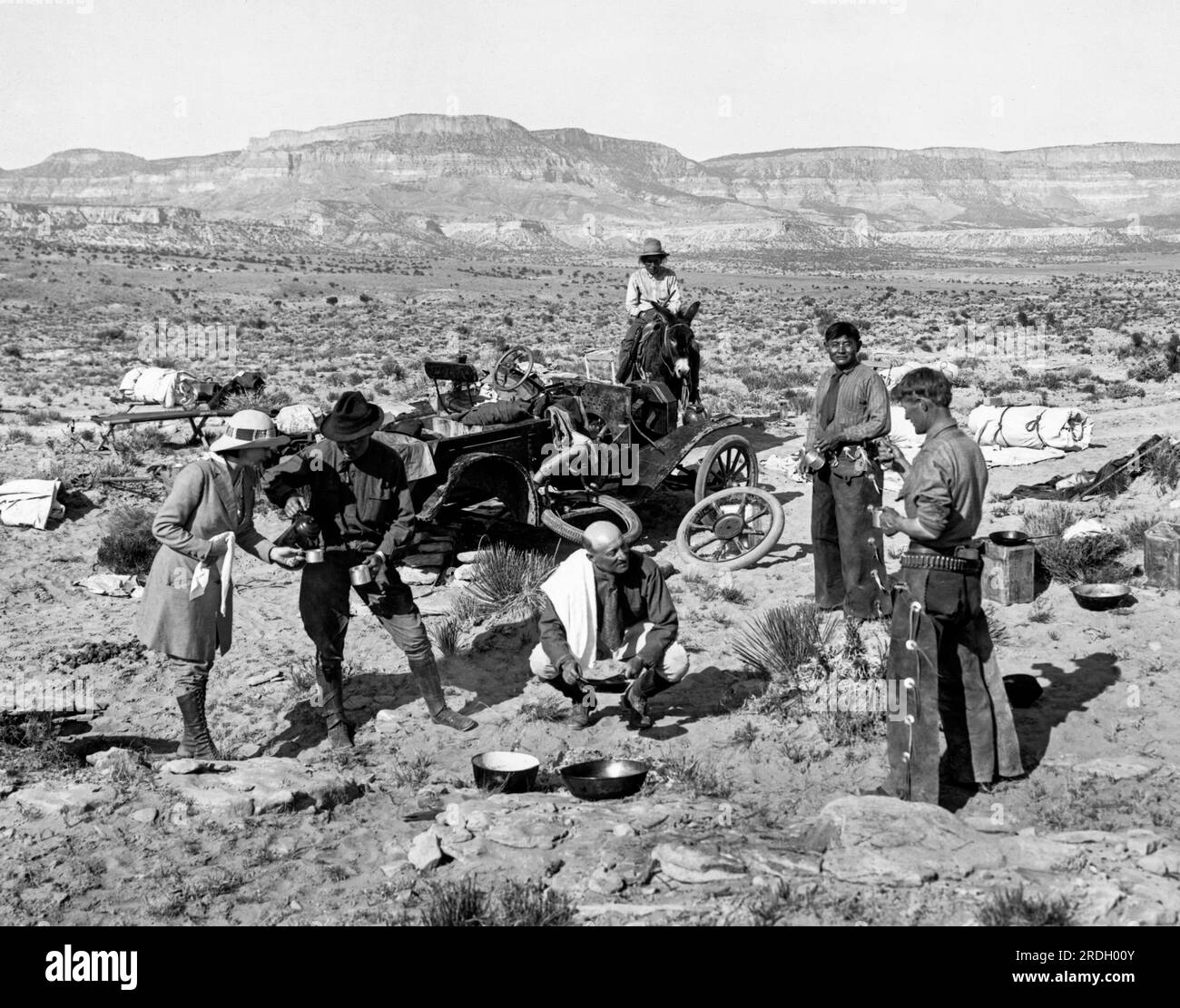 Kayenta, Arizona:   c. 1907 Cowboys stop to talk with two men and a woman with their broken down vehicle in the desert. Stock Photo