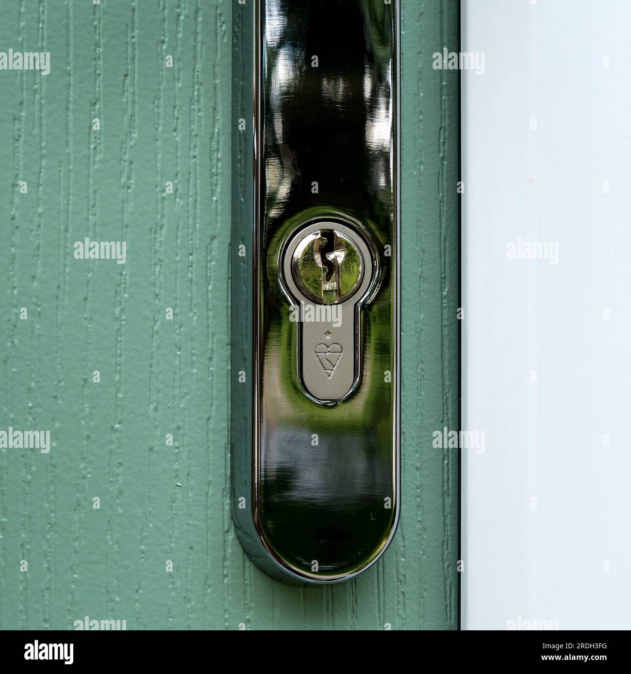 Closeup of British Standard kite marked pin tumbler euro profile cylinder lock fitted in silver front door handle. Stock Photo