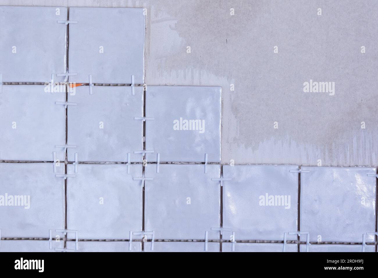 A portrait of an unfinished ceramic tile wall, with white plastic joint