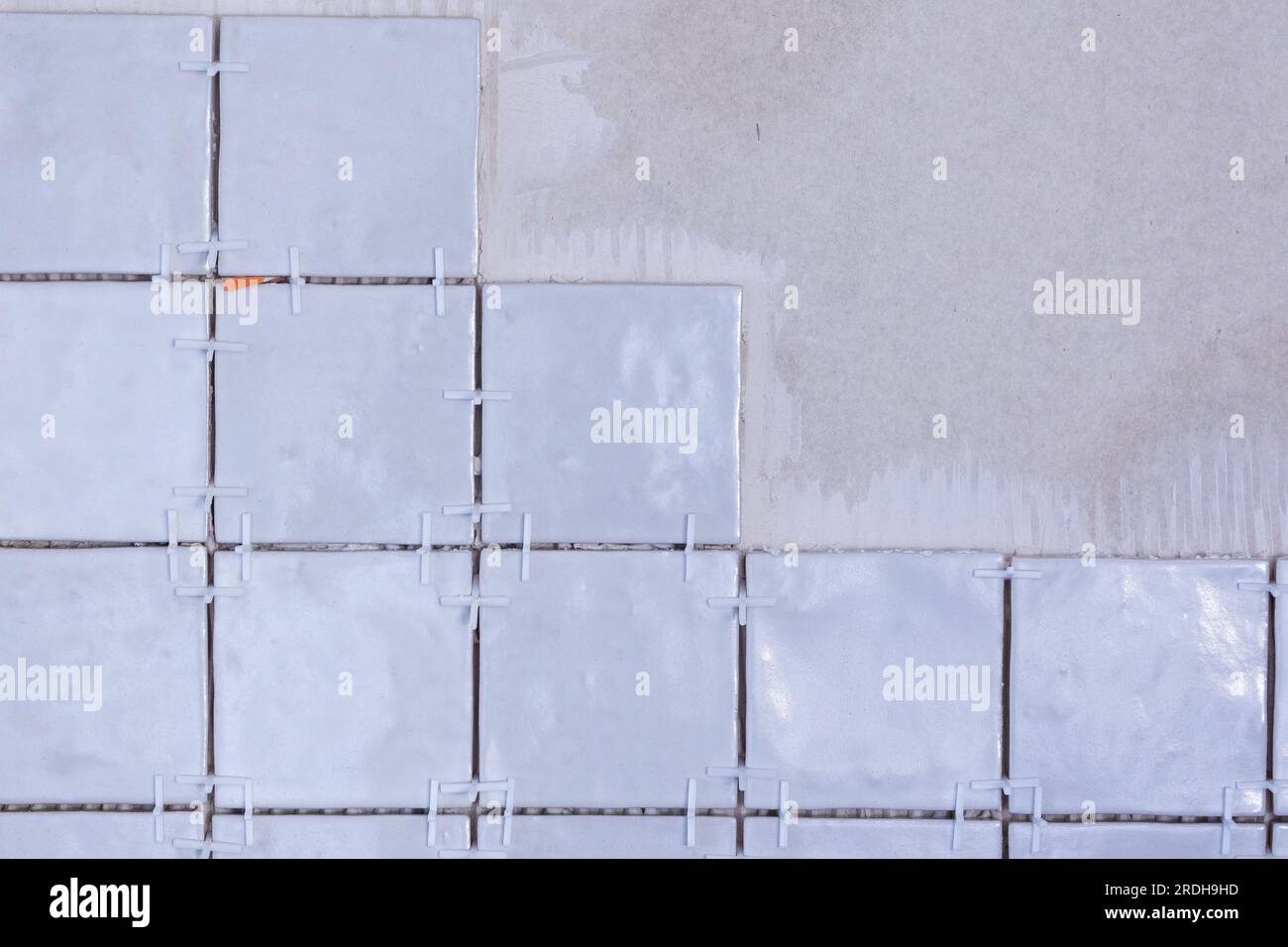 A portrait of an unfinished ceramic tile wall, with plastic white joint