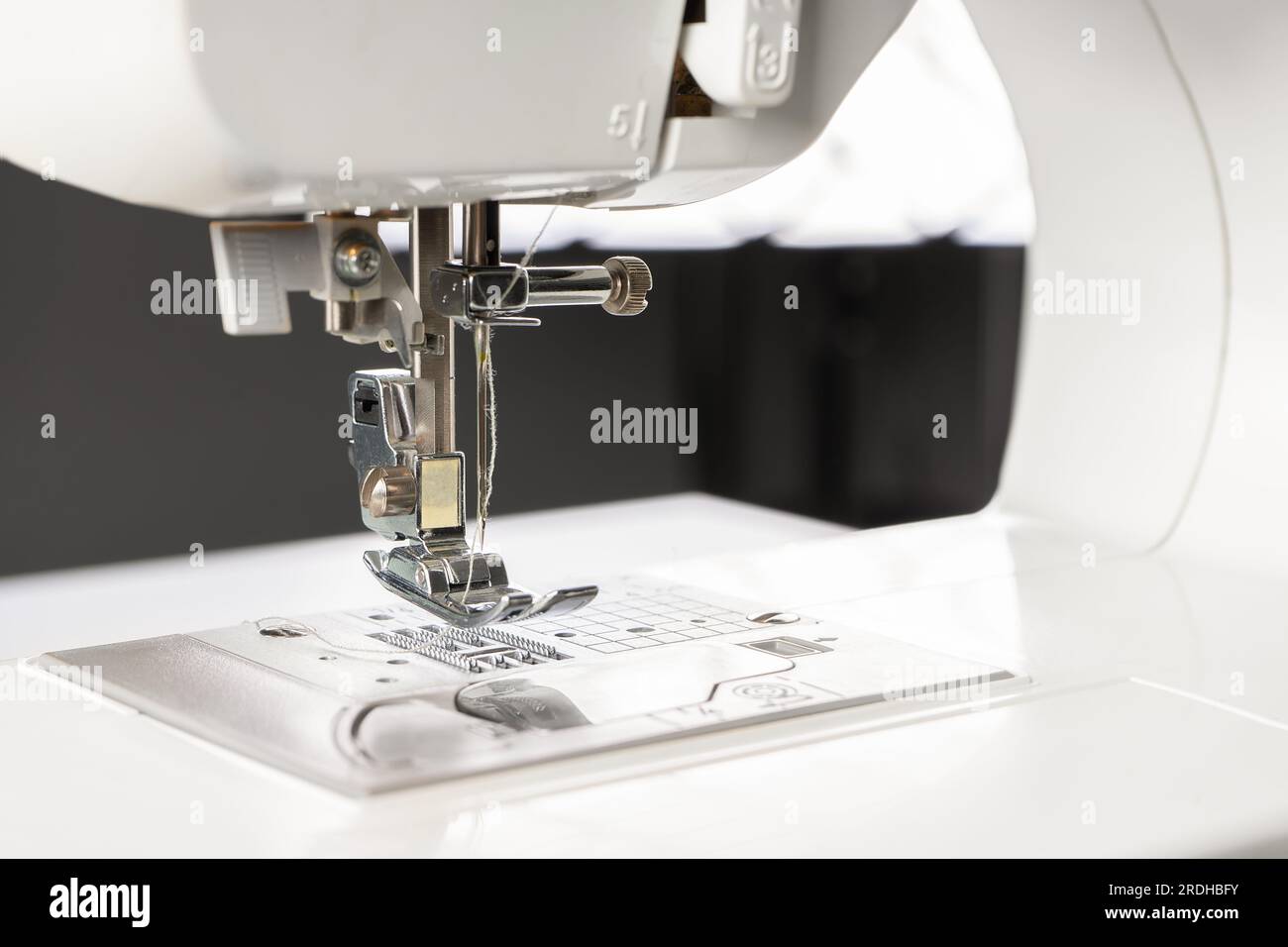 Modern white sewing machine presser foot closeup, macro. Sewing equipment, work tool for atelier