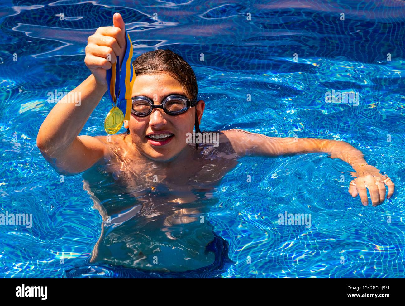 Successful caucasian young swimmer with award in outdoor pool. Golden
