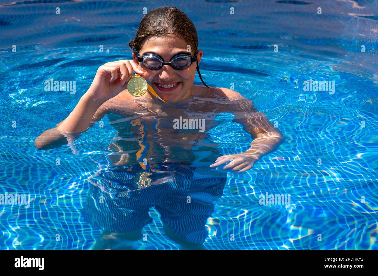 Successful caucasian young swimmer with award in outdoor pool. Golden ...